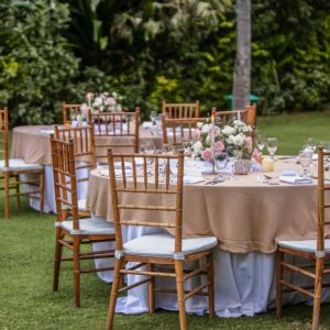 Beautiful outdoor wedding decoration in garden. Round tables decorated with candles, flowers and accessories. Open air wedding banquet on green lawn